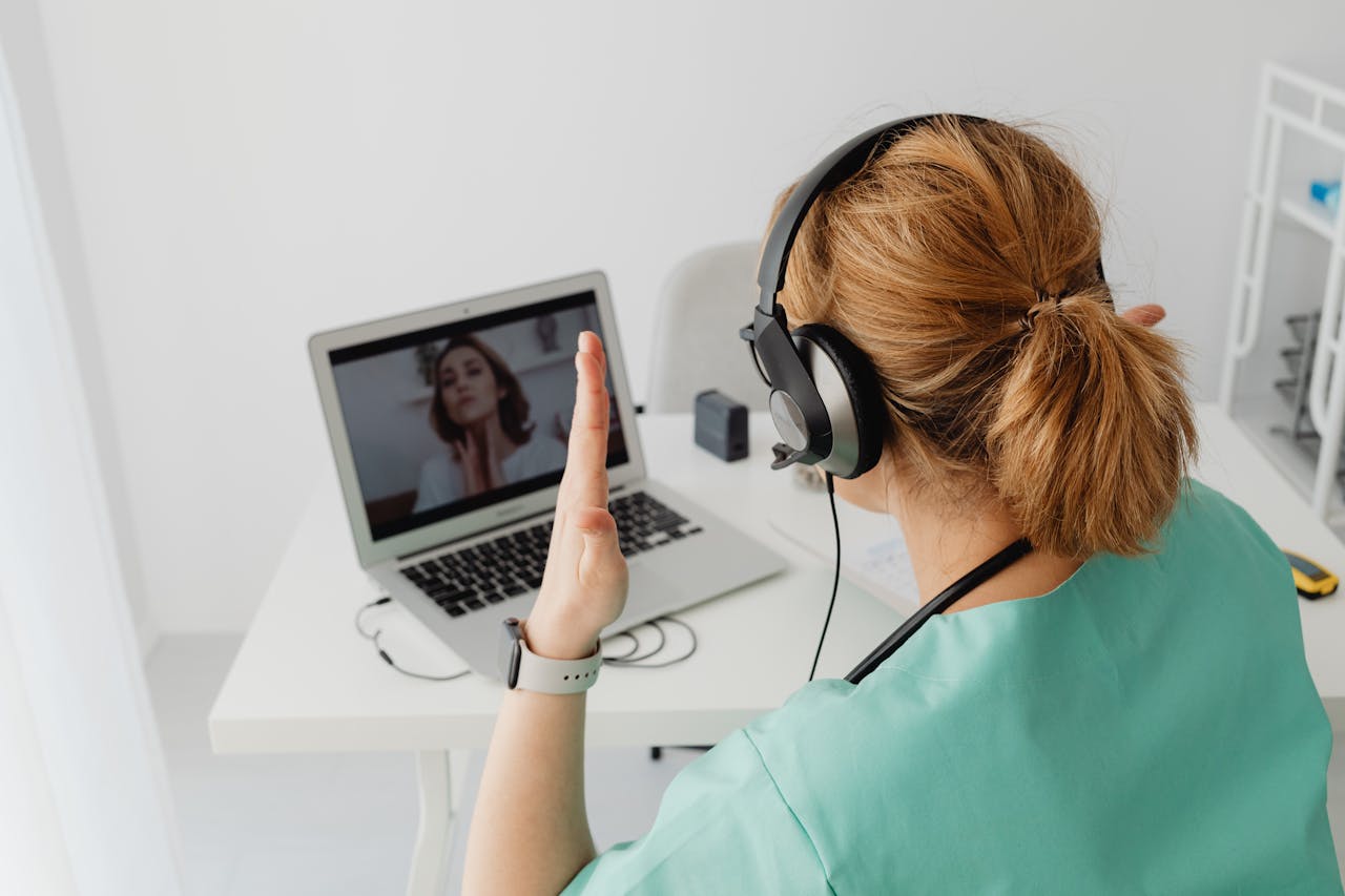 A female doctor engaged in a video call consultation with a patient on a laptop.